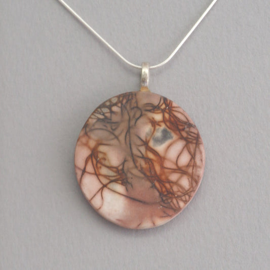 Unique smoke fired ceramic pendant with orange line pattern on a black necklace