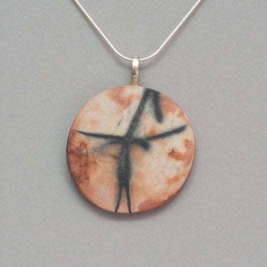 Smoke fired ceramic pendant with unique patterns from gas kiln firing on a silver chain.